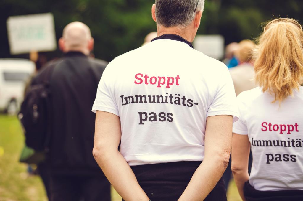 Ein Mann und eine Frau tragen "Stoppt Immunitätsausweis"-T-Shirts