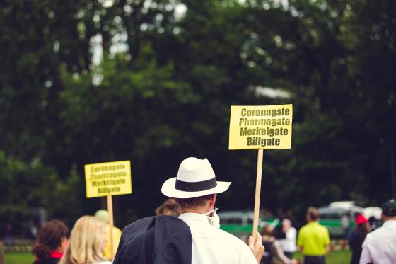 Ein Mann mit Corona-Protest-Schild, auf dem "Coronagate, Pharmagate, Merkelgate, Billgate" drauf steht.